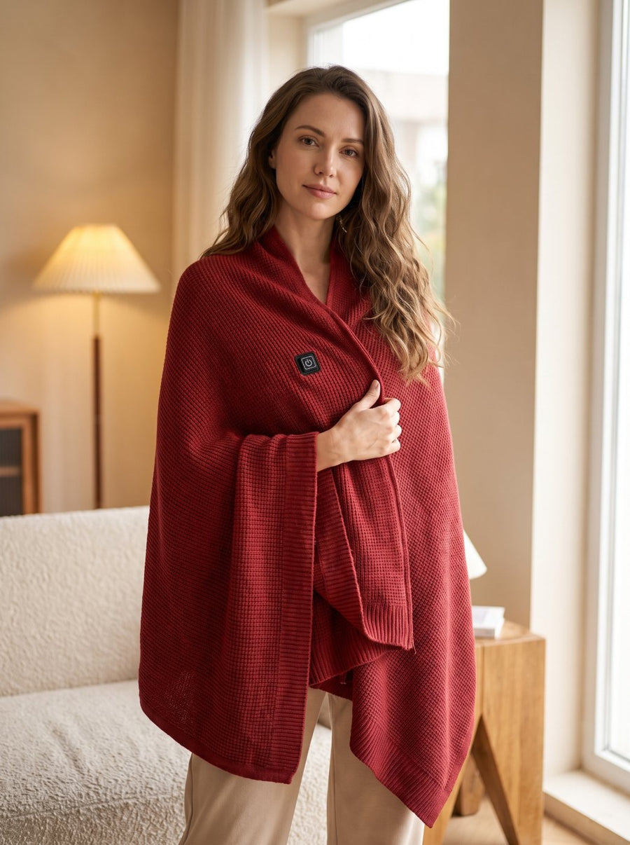Woman wearing the Thermora Heated Shawl in Maple Red beside a window